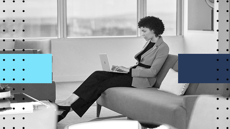 Image of a woman sitting on couch in an office setting working on a Surface Laptop Go 2