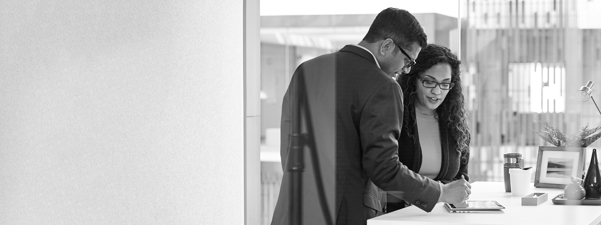 Two people looking at a tablet in an office.