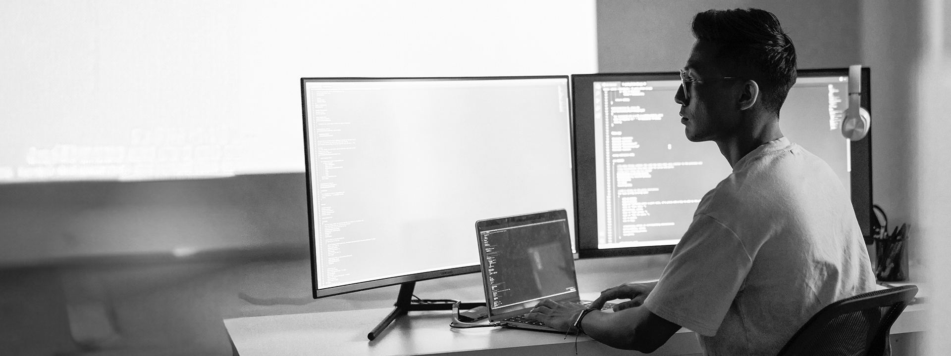 A man working on a computer with multiple monitors displaying code