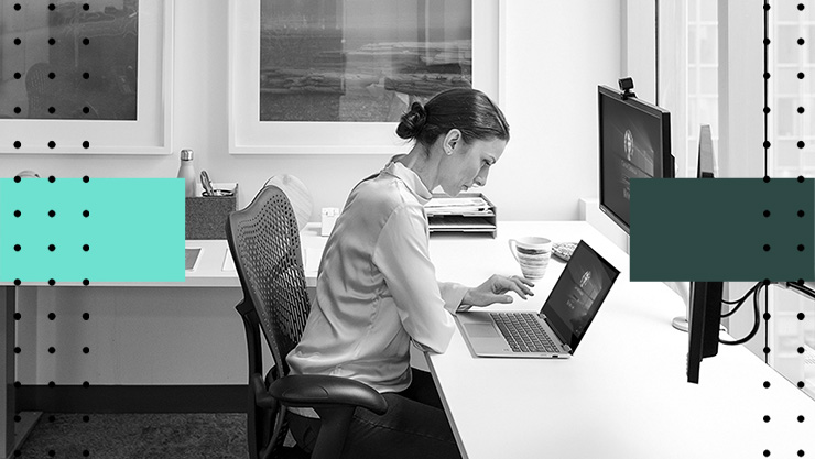 A woman working on a laptop at her desk