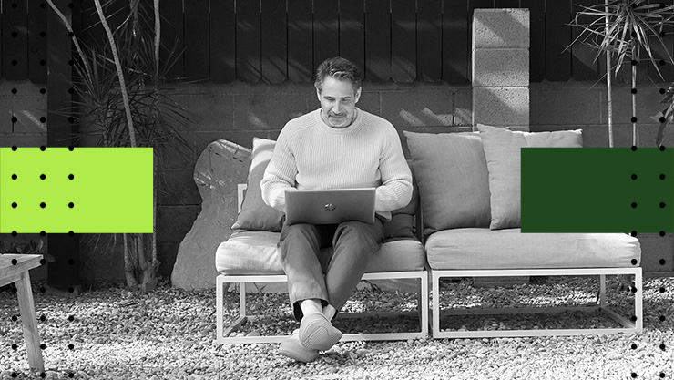 A man sitting in his yard using his laptop