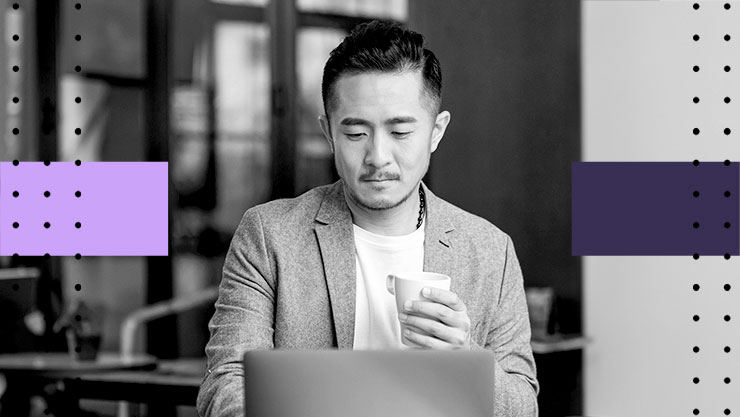 A man holding a mug and looking at his laptop