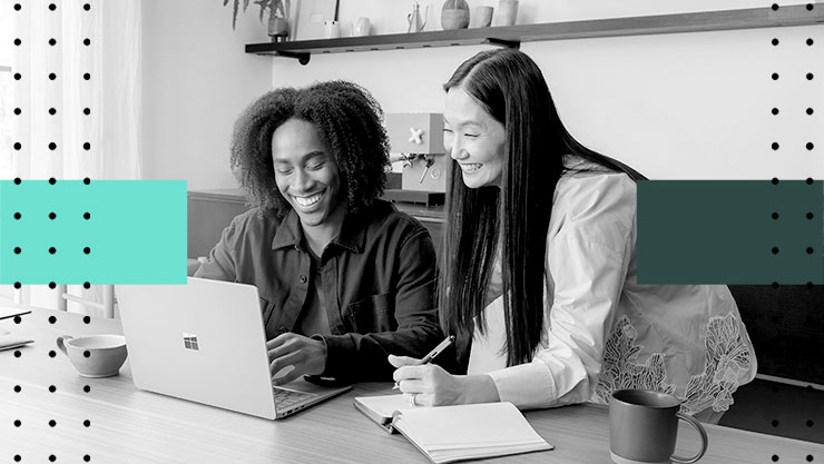 Two smiling people looking at a laptop screen