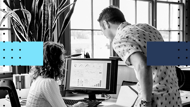 Two people in an office looking at a data dashboard on a computer screen