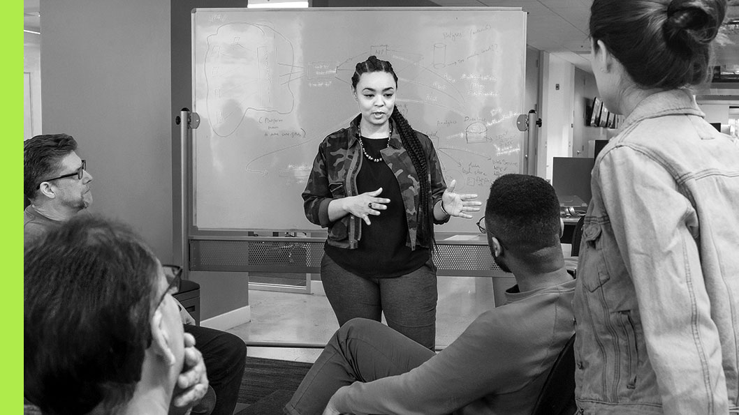 A group of people in an office listening to a presentation