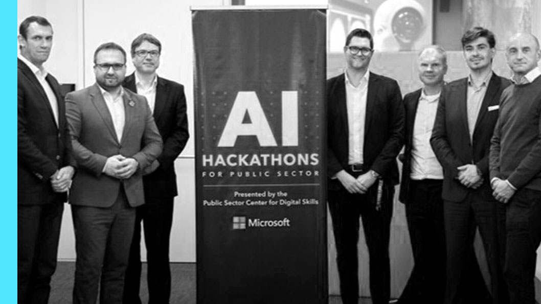 A group of people standing around a banner that reads "AI Hackathons for Public Sector Presented by the Public Sector Center for Digital Skills Microsoft”