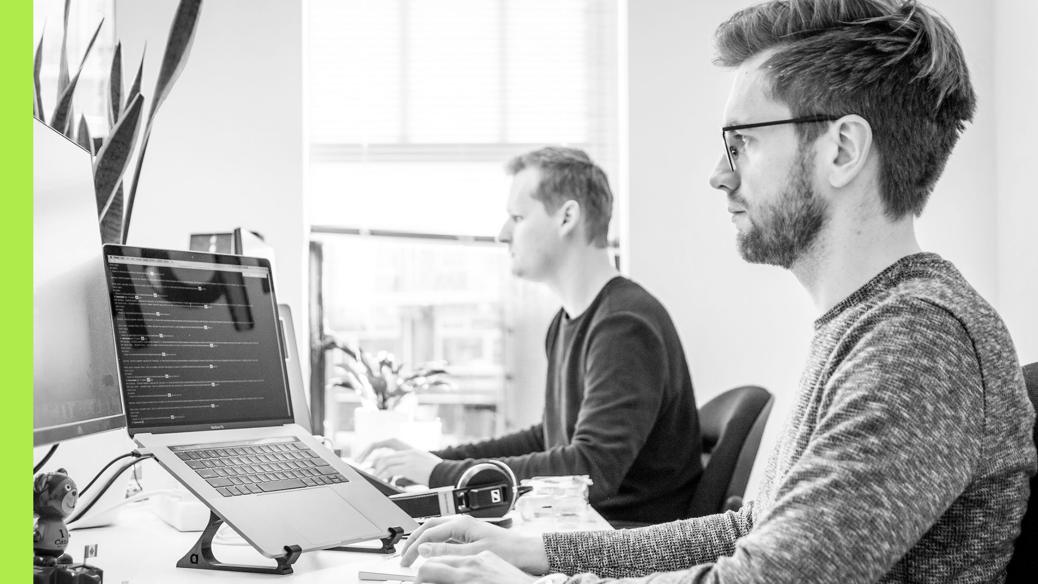 Two people working at a desk on their laptops.