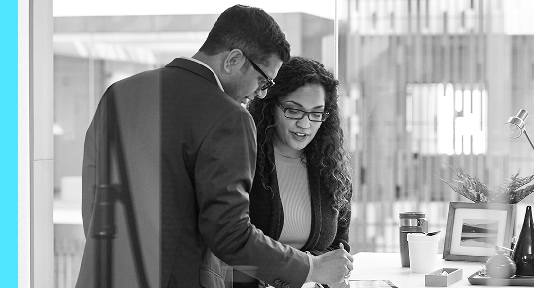 Two people looking at a tablet in an office.