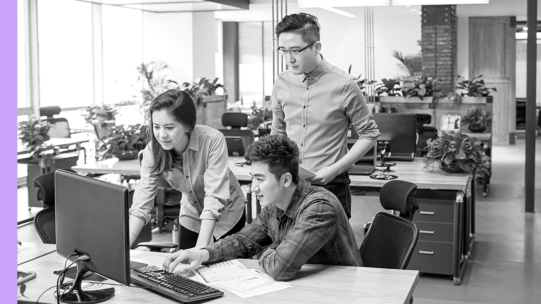 A group of people looking at a computer monitor