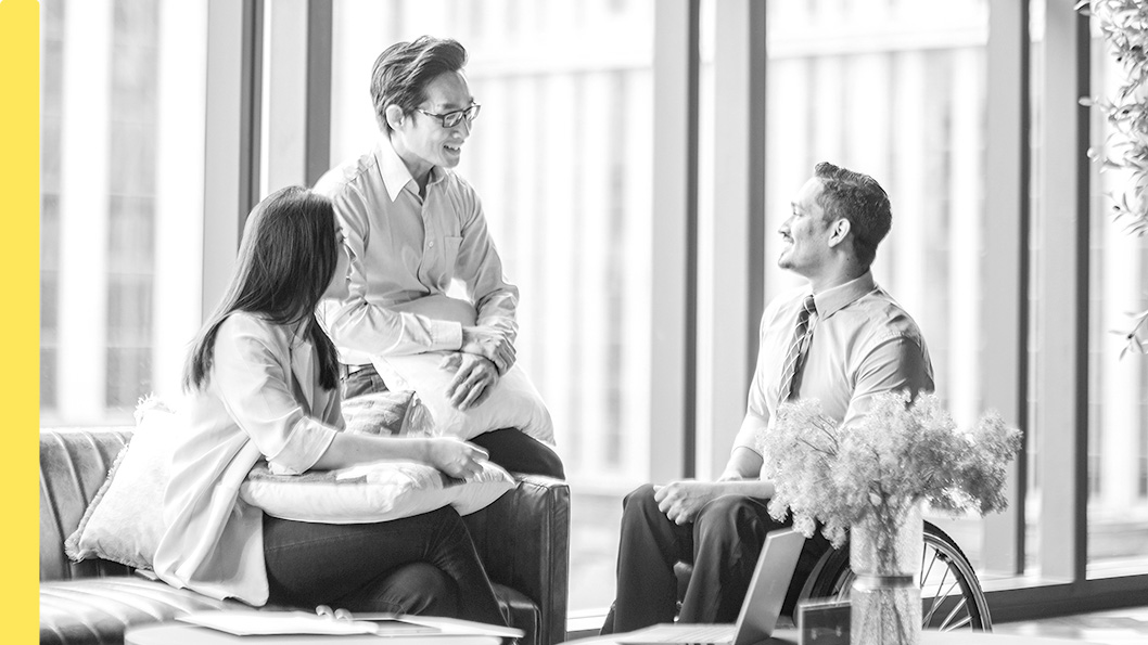 Three people having a conversation in an office