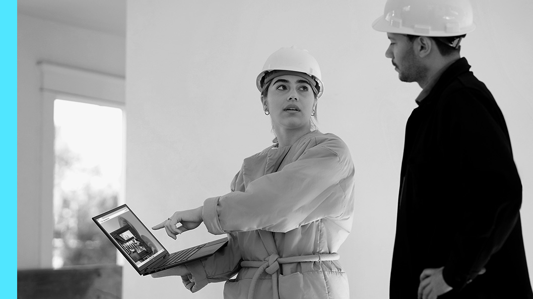 Two people in hardhats looking at a laptop