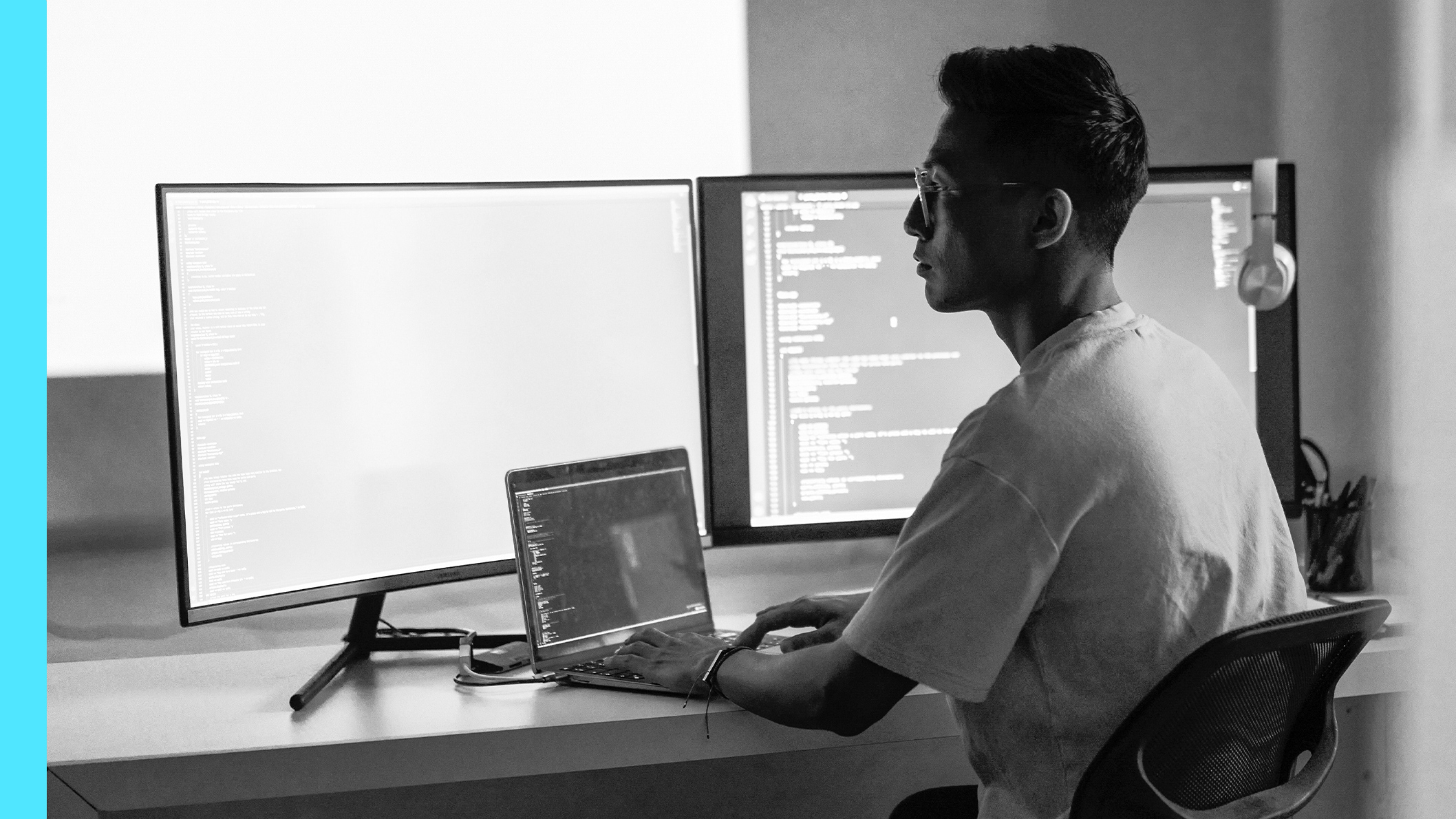 A man working on a computer with multiple monitors displaying code.