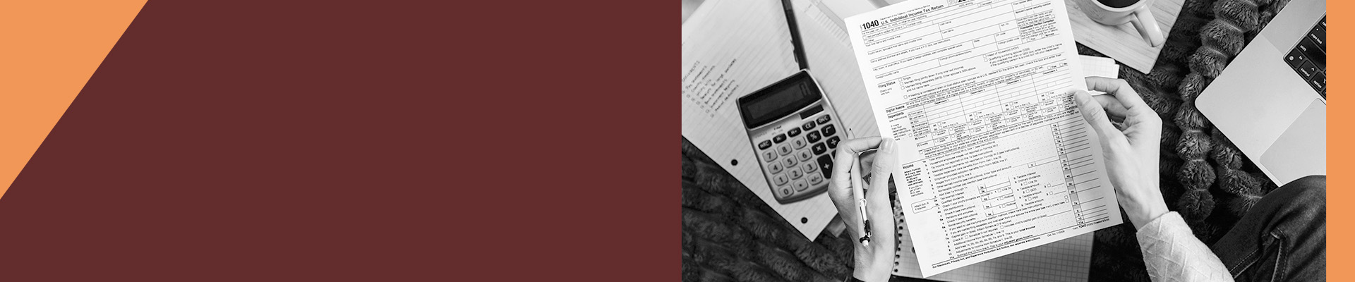 Hands holding a 1040 tax form over a desk with a calculator, notebook, coffee cup, and laptop in a black‑and‑white workspace.