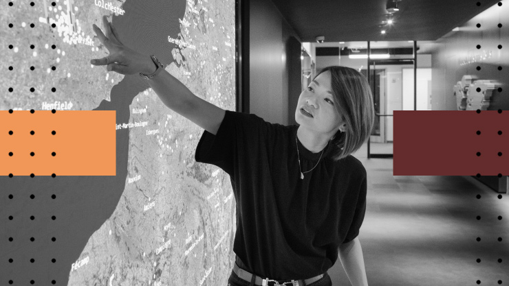 Woman gesturing toward a large digital map display in a modern office space